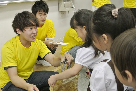 子どもに養蜂の説明をしている大学生