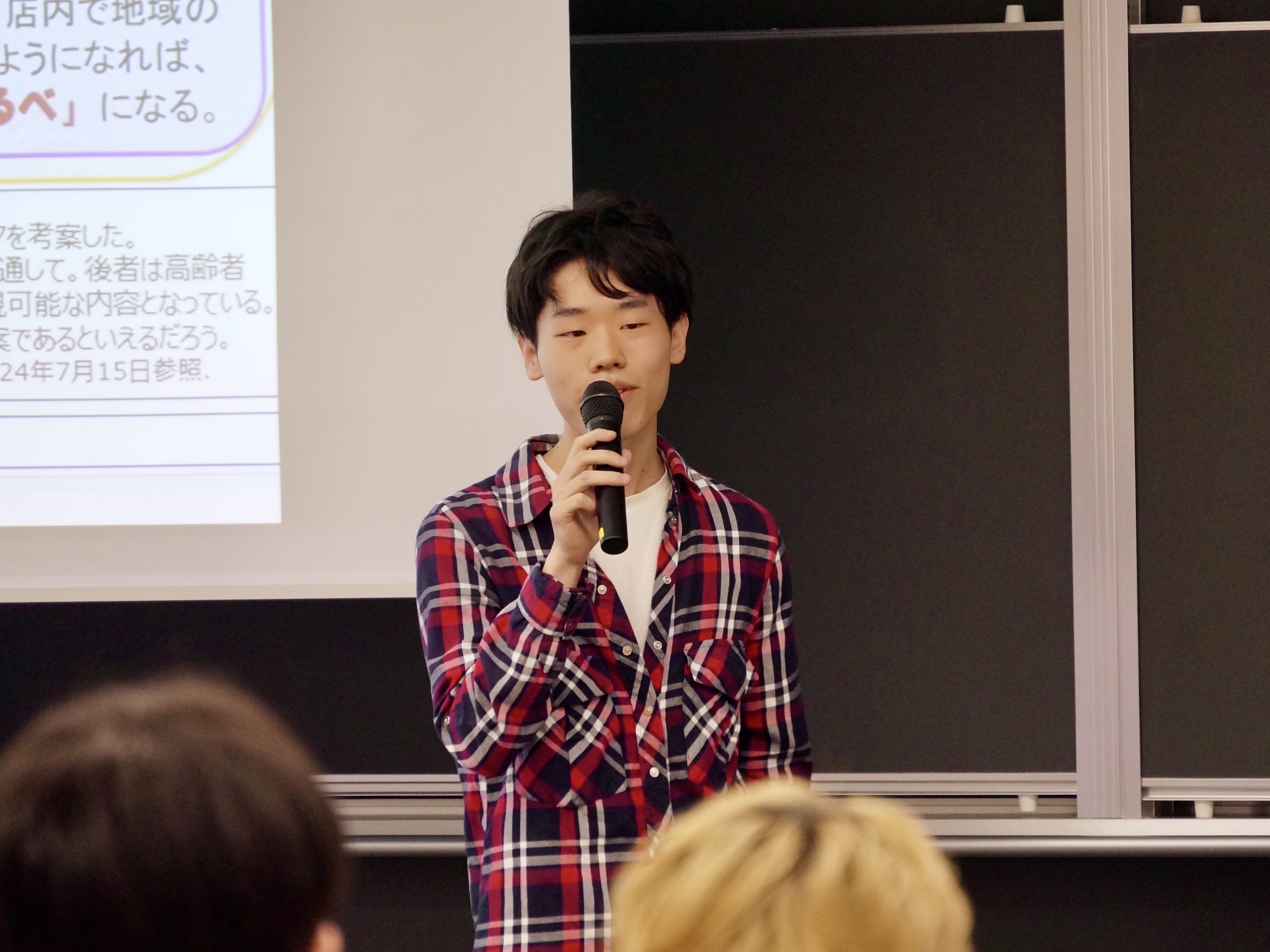マイルポストを活用した地域交流促すアイデアについて、学生が説明している