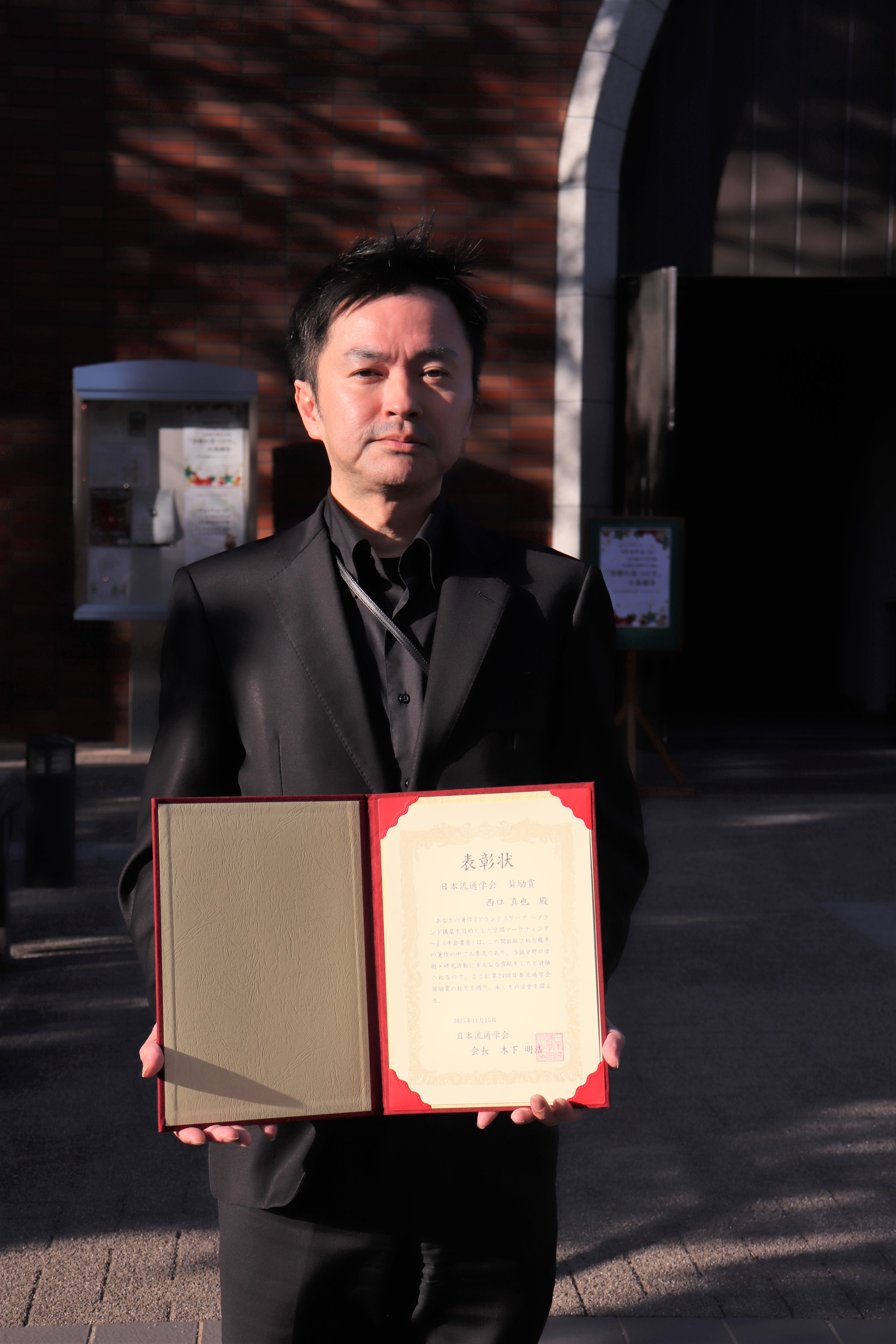 商学部西口先生が賞状を持っている様子